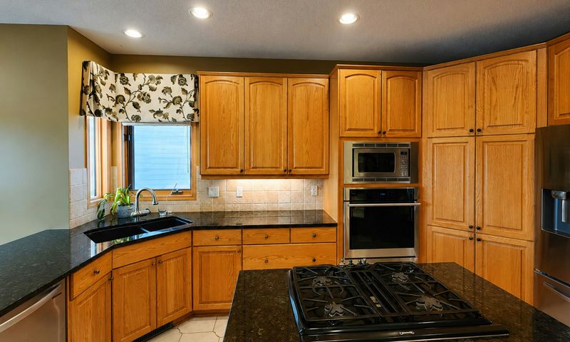 Black granite countertops and cooktop island with honey oak cabinets